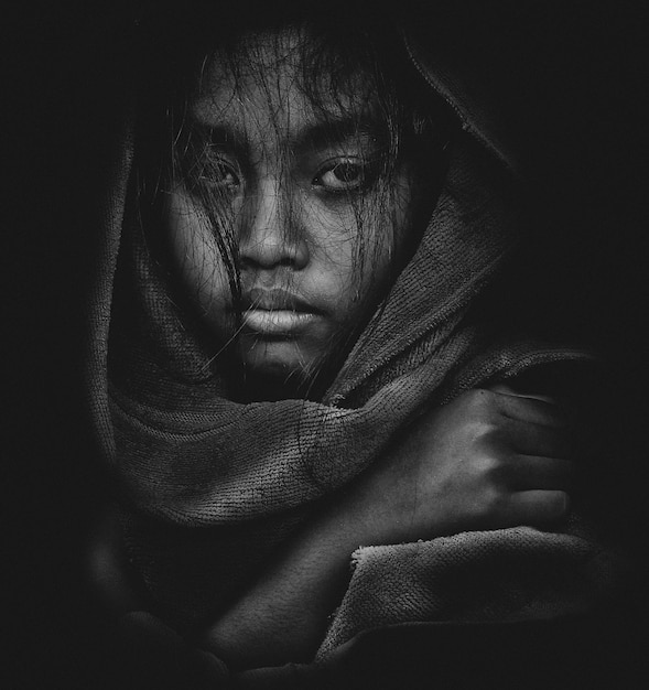 close-up portrait of woman wearing headscarf against black background