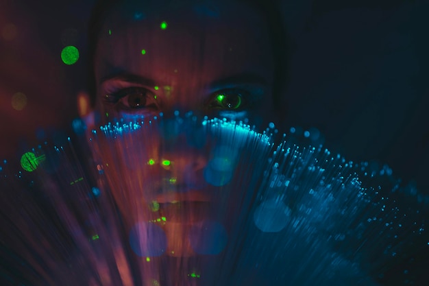 Close-up portrait of young woman against illuminated background