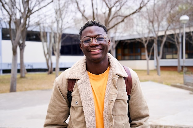 close up shot of cheerful happy african american teenage boy looking at camera smiling intense look of a young student man at campus university high school