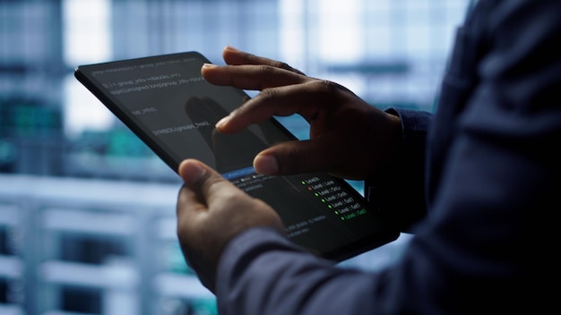 close up shot of worker in server room using tablet