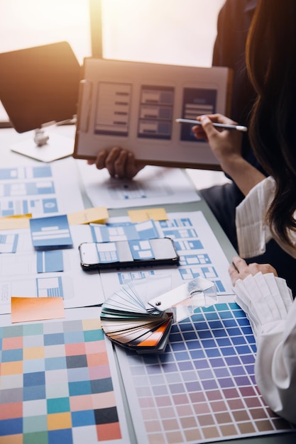 Close up ux developer and ui designer brainstorming about mobile app interface wireframe design on table with customer breif and color code at modern officeCreative digital development agency