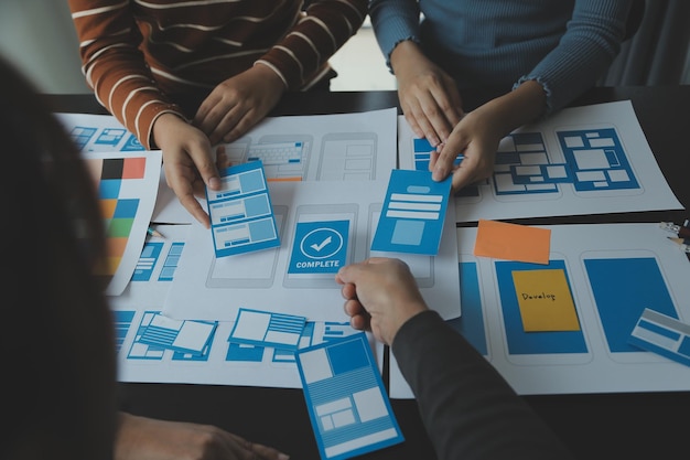 Close up ux developer and ui designer brainstorming about mobile app interface wireframe design on table with customer breif and color code at modern officeCreative digital development agency