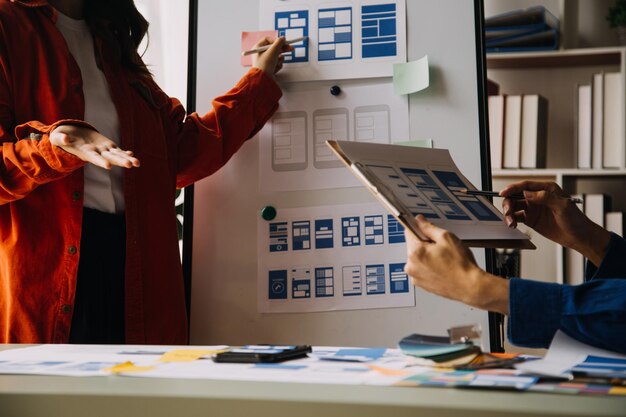 Close up ux developer and ui designer brainstorming about mobile app interface wireframe design on table with customer breif and color code at modern officeCreative digital development agency