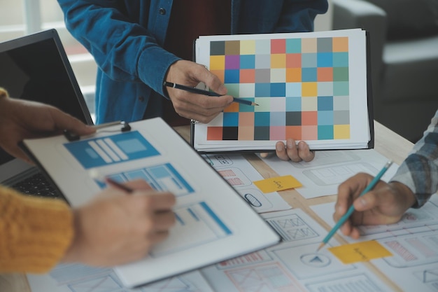 Close up ux developer and ui designer brainstorming about mobile app interface wireframe design on table with customer breif and color code at modern officeCreative digital development agency