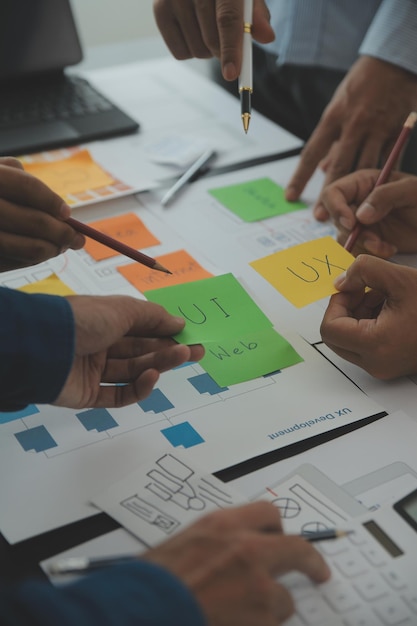 Close up ux developer and ui designer brainstorming about mobile app interface wireframe design on table with customer breif and color code at modern officeCreative digital development agency