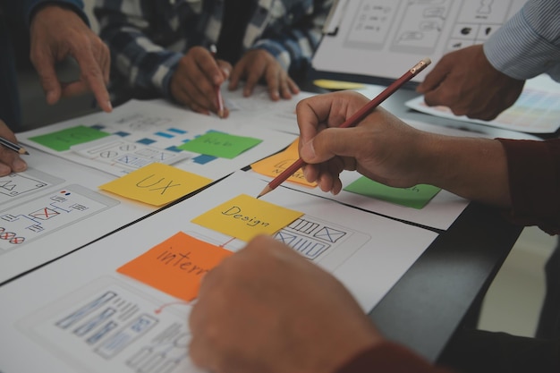 Close up ux developer and ui designer brainstorming about mobile app interface wireframe design on table with customer breif and color code at modern officeCreative digital development agency