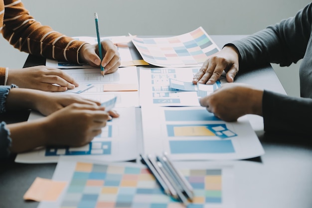 close up ux developer and ui designer brainstorming about mobile app interface wireframe design on table with customer breif and color code at modern officecreative digital development agency