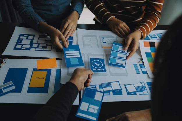 Close up ux developer and ui designer brainstorming about mobile app interface wireframe design on table with customer breif and color code at modern officeCreative digital development agency