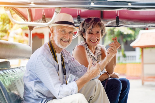Closeup American senior tourist man with his friend European poses happy thumbs up and mini heart
