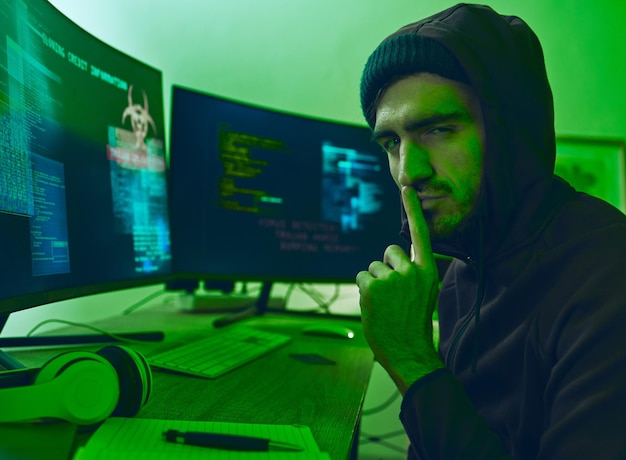 Computer hacker neon and portrait of a man with secret for hacking phishing or cybersecurity software Dark finger on lips and person with information on pc for ransomware privacy or programming