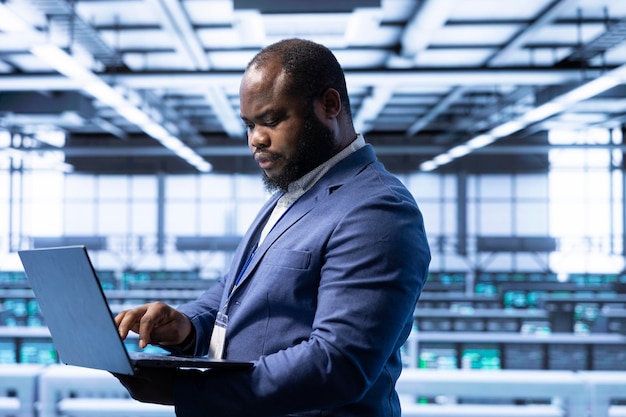 Computer scientist using laptop in data center with advanced tech