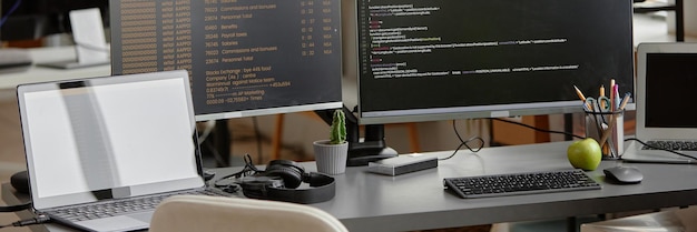 Computers with lines of code running on screens in software engineer workspace