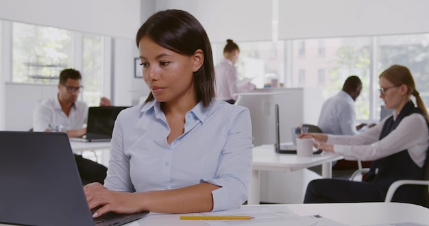 Concentrated AfricanAmerican american businesswoman sitting at desk in office working on laptop