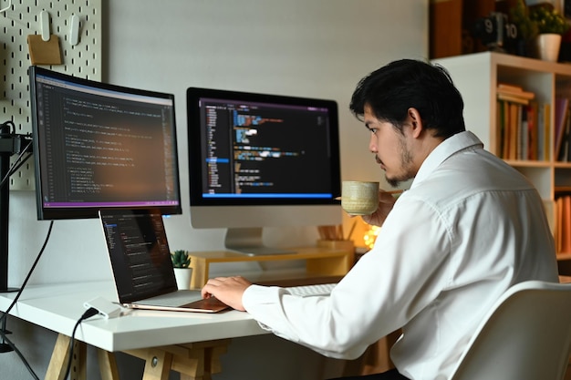 Concentrated male web developer working with coded data on computer screen Programming and coding technologies