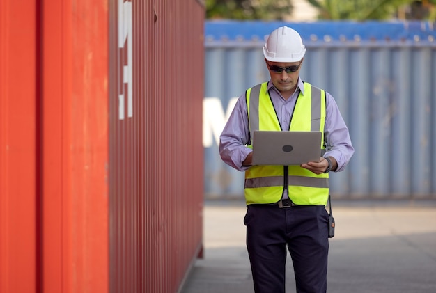 Confident caucasian man engineer wearing white safety helmet using computer laptop  transport