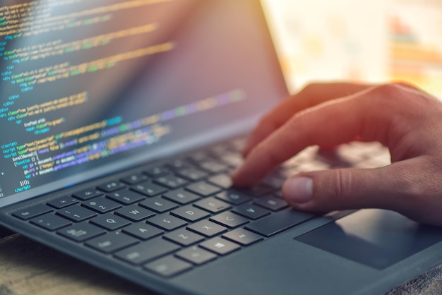 cropped hand of computer programmer coding on laptop