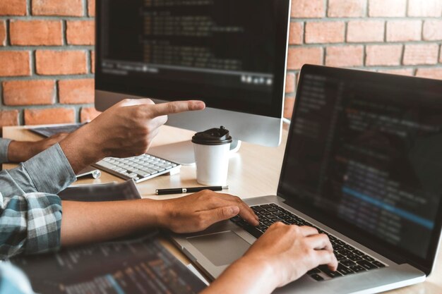 Cropped hands of coworkers using laptop and computer in office
