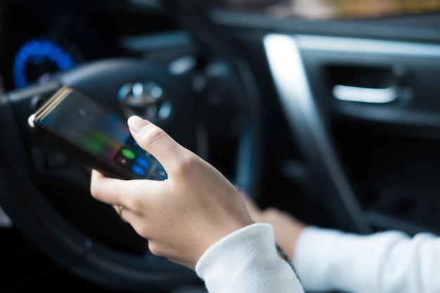 Cropped hands using smart phone in car
