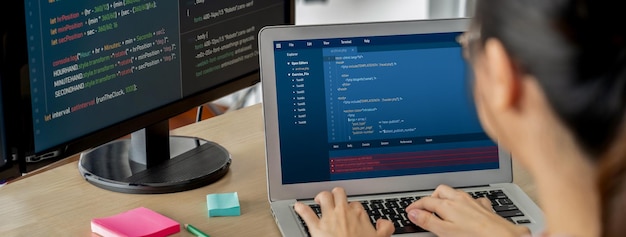 cropped image of female web developer coding on laptop while computer displayed program and software code at modern office close up businesswoman hand focus on analysis data burgeoning