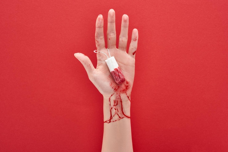 Photo cropped view of woman holding tampon with blood on red background