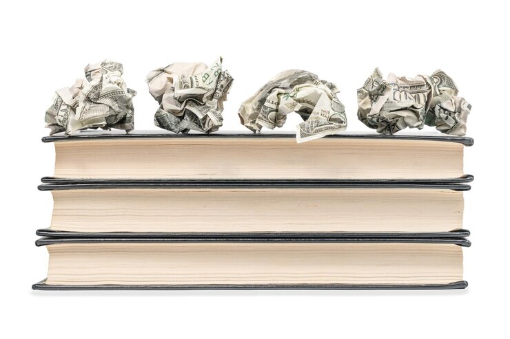 Photo crumpled money lying on top of a pile of closed books isolated on a white background