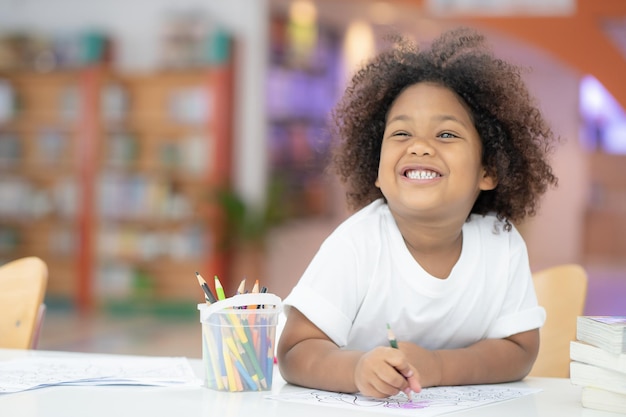 Cute girl coloring while sitting at table