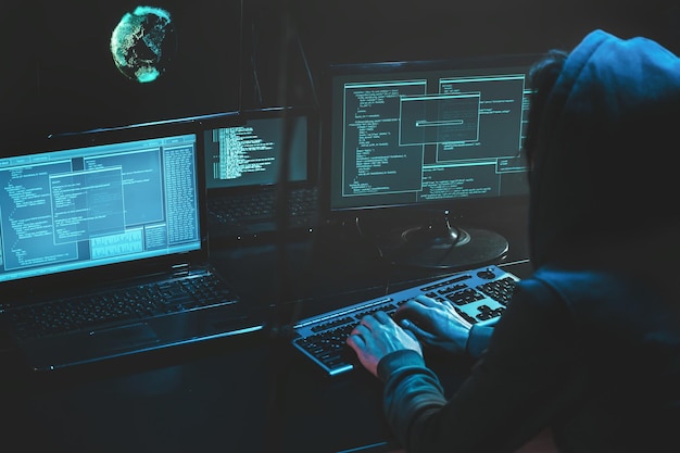 Cyber criminal hacking system at monitors hacker attack web servers in dark room at computer with monitors sending virus using email vulneraility Internet crime hacking and malware concept