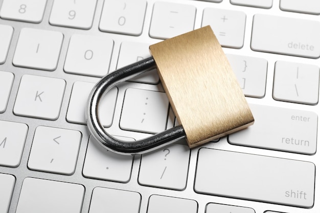 Cyber security Metal padlock and keyboard on table closeup