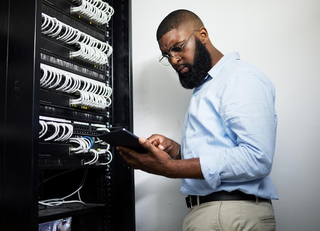 Data center tablet and serious technician man with cables for internet connection for software programming Engineer black person with tech for cybersecurity wire or problem solving in server room