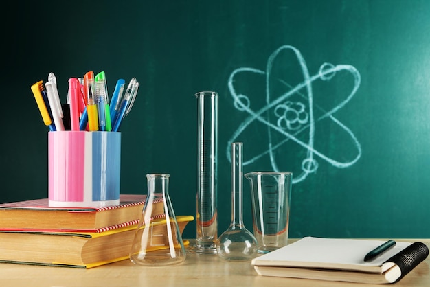 Desk in chemistry class with test tubes on green blackboard background