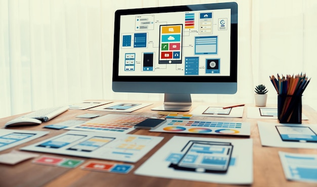 Digital and paper wireframe designs for web or mobile app UI UX display on laptop computer screen Panoramic shot of developer workspace for brainstorming and design application framework Scrutinize