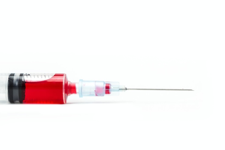 Photo disposable syringe with a red liquid inside on a white background