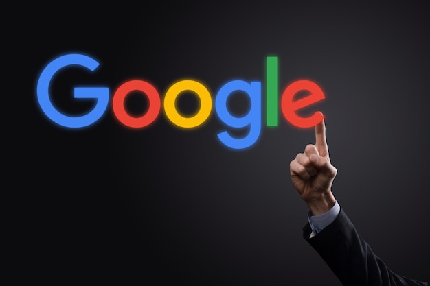Doanh nhân mặc vest trên nền tối cầm dòng chữ logo Google. Google là công cụ tìm kiếm phổ biến nhất thế giới.