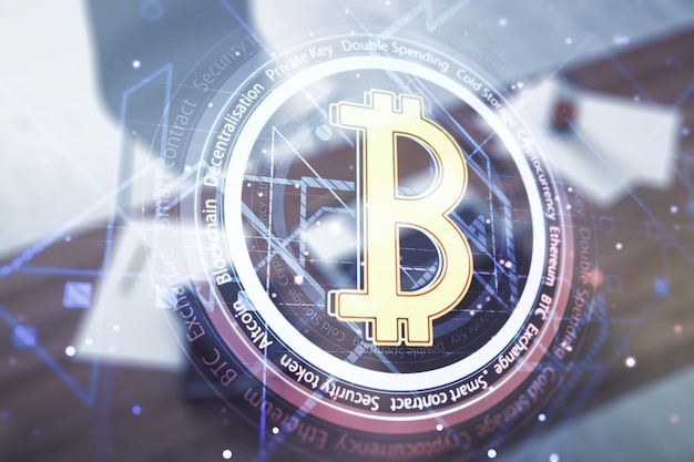Double exposure of creative Bitcoin symbol and modern desktop with laptop on background Cryptocurrency concept