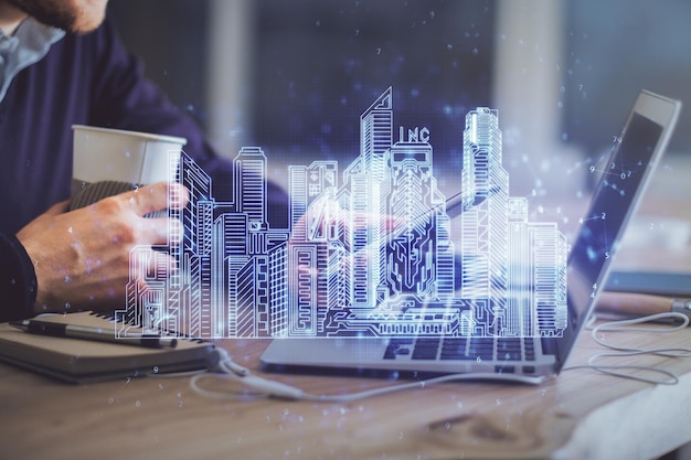 Double exposure of mans hands holding and using a digital device and city drawing
