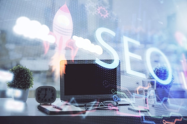 double exposure of table with computer and seo drawing hologram search optimization concept