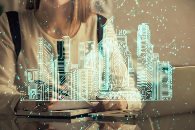 Double exposure of woman hands typing on computer and buildings drawing Smartcity concept