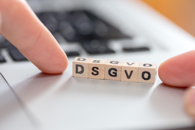DSGVO Wooden cubes with letters DSGVO lying on a laptop Datenschutzgrundverordnung