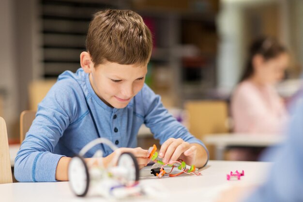 education, children, technology, science and people concept - close up of boy building robot at robotics school lesson