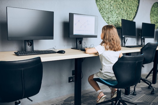 Engaged schoolgirl learning to use technology in classroom at primary school back to school
