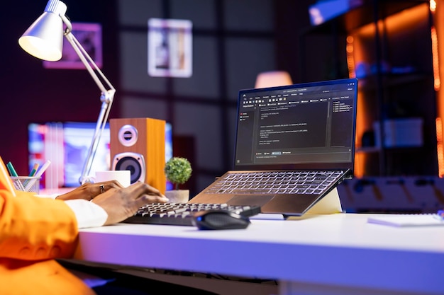 Engineer at desk typing code on notebook device developing software programs entering commands