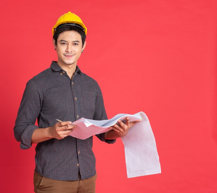 Photo engineering man with blueprint on red wall.