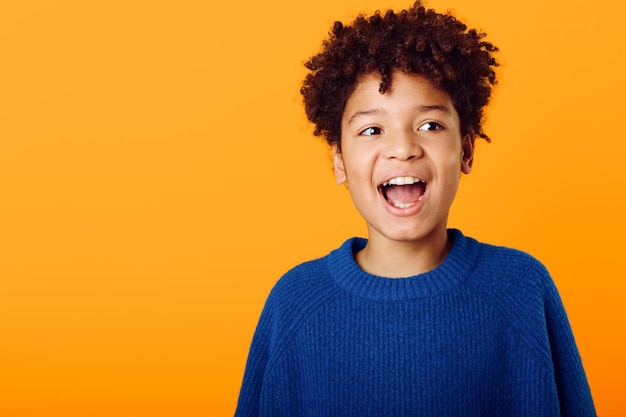 excited young african american boy with his mouth wide open in surprise against a vibrant orange background