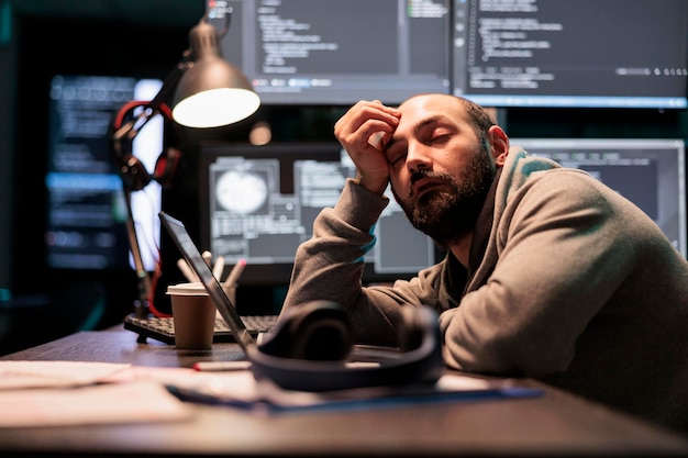 exhausted app developer feeling sleepy late at night, falling asleep in office writing code on terminal window. tired overworked programmer working after hours with artificial intelligence.