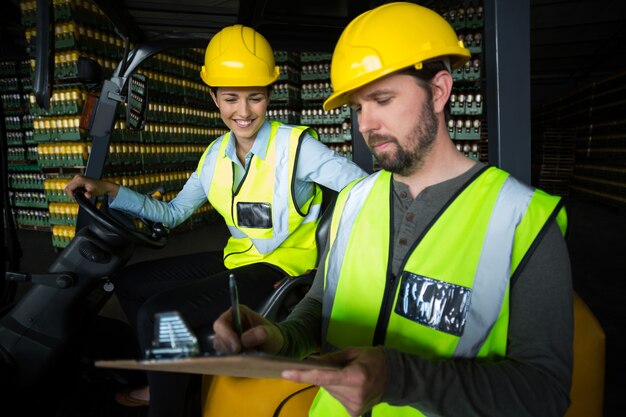 Factory workers maintaining record on clipboard in factory