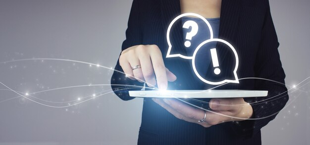 faq frequently asked questions concept. white tablet in businesswoman hand with digital hologram faq question answer sign on grey background. quiestions online