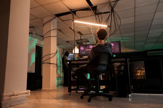 Female hacker working to steal server passwords, coding virus to create malware at night. Young thief planting malicious software and breaking into computer system, security breach.