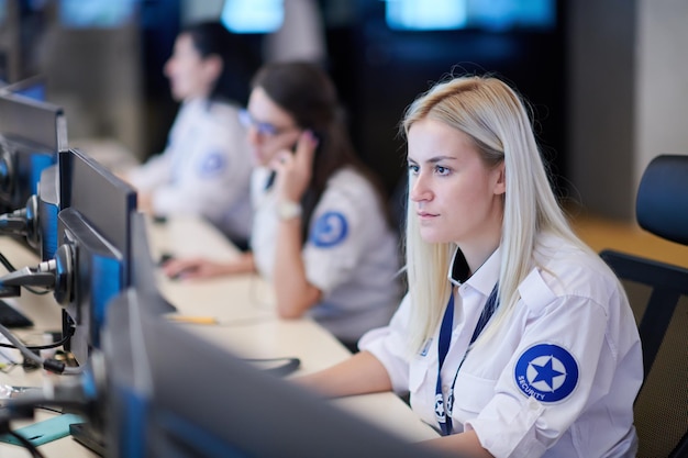Female security operator working in a data system control room offices Technical Operator Working at  workstation with multiple displays, security guard working on multiple monitors