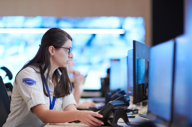Female security operator working in a data system control room offices Technical Operator Working at  workstation with multiple displays, security guard working on multiple monitors