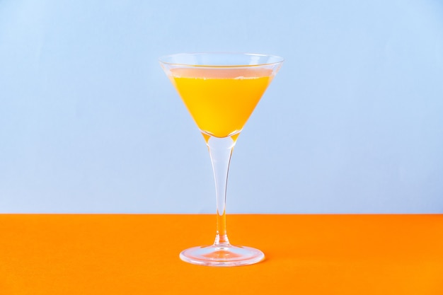 Fresh orange juice in glass on orange surface